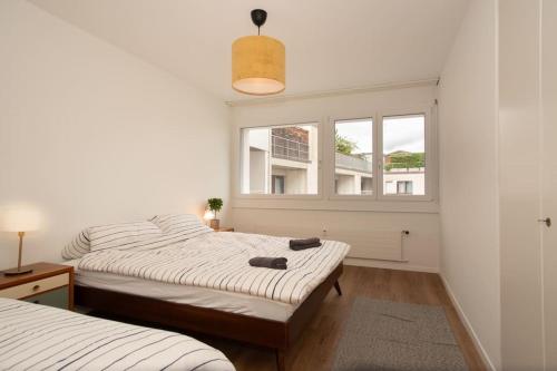 two beds in a room with a window at Spacious apartment next to Rhine in Basel