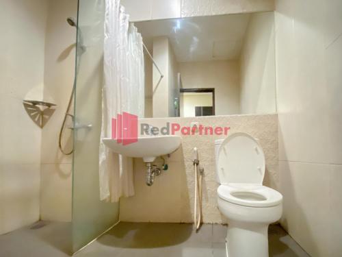 Łazienka z białą toaletą i umywalką w obiekcie Hotel Alpha Makassar RedPartner w mieście Makasar