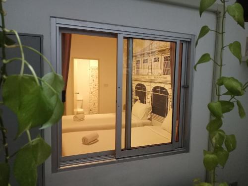 a window with a view of a bed at Chino Town Gallery Alley - SHA Plus in Phuket