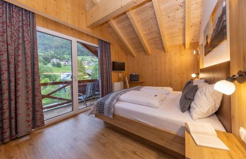sypialnia z łóżkiem i dużym oknem w obiekcie Wellness- und Familienhotel Dachsteinresort w mieście Rußbach am Paß Gschütt