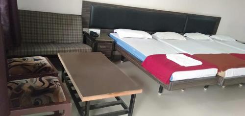 a bedroom with a bed and a table and a couch at iROOMZ Hoysala Residency in Bellary