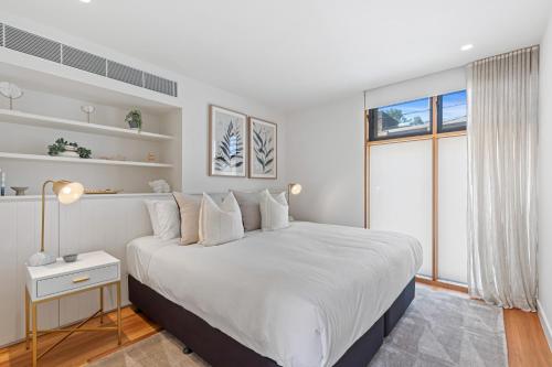 Un dormitorio blanco con una cama grande y una ventana en Stylish 2-bed Victorian Terrace in Carlton en Melbourne