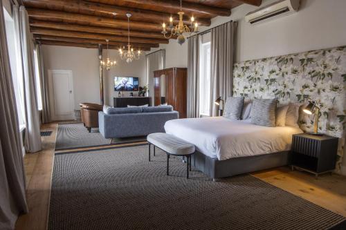 a bedroom with a bed and a couch and a television at Laborie Jonkershuis in Paarl