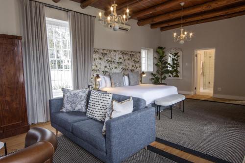 a bedroom with a bed and a couch and a chair at Laborie Jonkershuis in Paarl