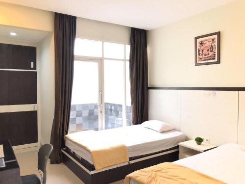 Habitación de hotel con 2 camas y ventana en RedDooz Plus At Ininnawa Homestay Syariah Palu en Palu
