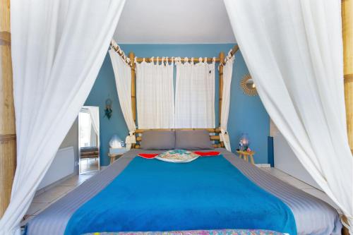 a bedroom with a blue bed with white curtains at Mb Room - Appartement jacuzzi 4 étoiles Beauté in Puget-sur Argens