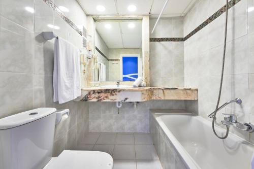 a bathroom with a tub and a toilet and a sink at Hotel Clumba in Cala Ratjada