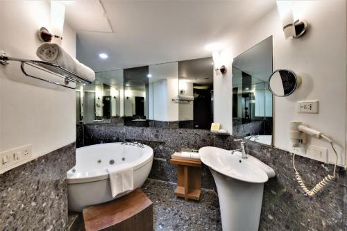 a bathroom with a tub and a sink and mirror at The Fern Residency, Subhash Bridge, Ahmedabad in Ahmedabad