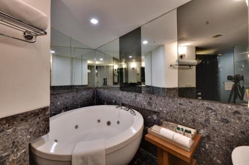 a bathroom with a tub and a large mirror at The Fern Residency, Subhash Bridge, Ahmedabad in Ahmedabad