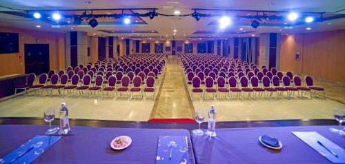 an empty auditorium with purple chairs and tables and wine glasses at Holiday World Polynesia in Benalmádena