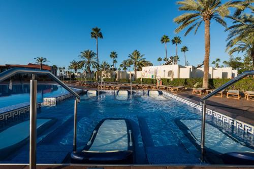 una piscina con un tobogán en un complejo con palmeras en HD Parque Cristobal Gran Canaria en Playa del Ingles