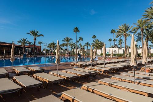 een zwembad met ligstoelen en parasols bij HD Parque Cristobal Gran Canaria in Playa del Inglés