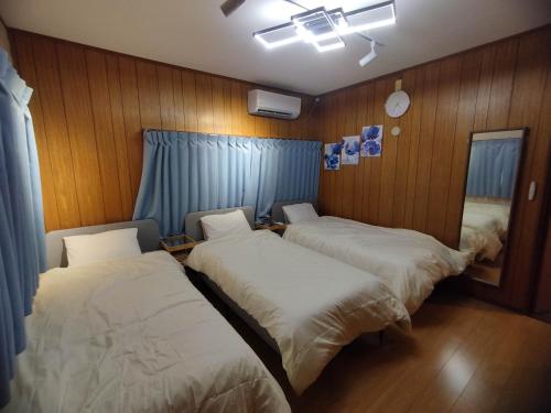 dwa łóżka w pokoju z drewnianymi panelami w obiekcie HIDAKA STAY VILLA 柴又 w Tokio
