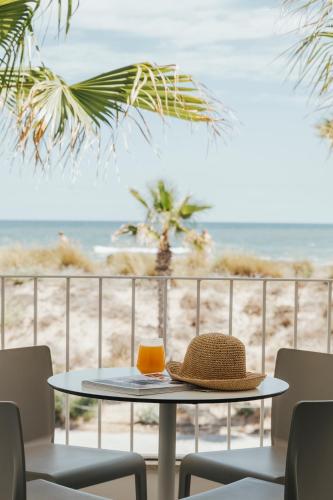 a straw hat sitting on a table in front of the beach at Kiko Park Oliva in Oliva