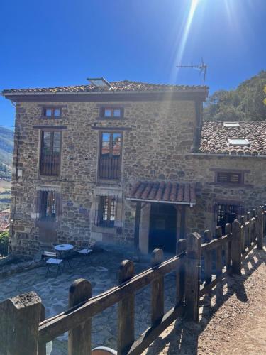 a stone house with a wooden fence in front of it at Casa Rural Basiver - Habitación Pico San Carlos in Armaño