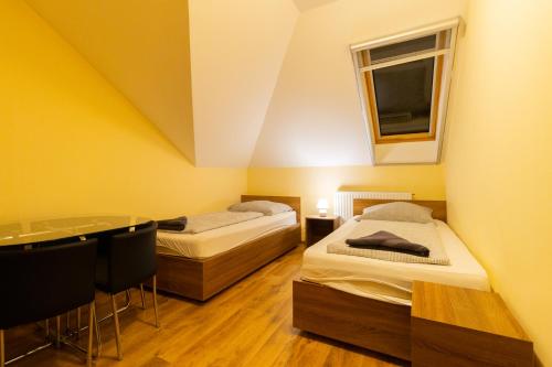 two beds in a room with a window and a table at Szelidi Apartmanok in Dunapataj