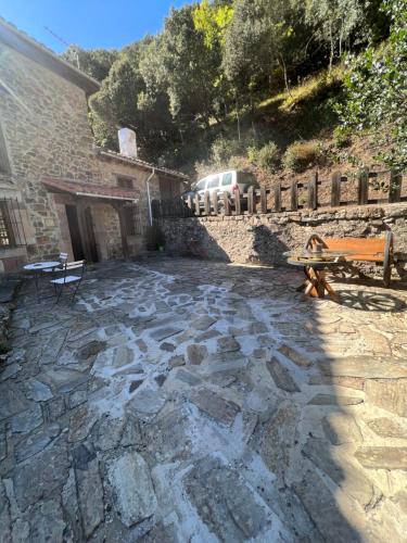 a stone patio with a bench and a building at Casa Rural Basiver - Habitación Pico San Carlos in Armaño