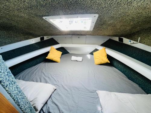 a small bed in the back of a boat with yellow pillows at Falua in Barcelona