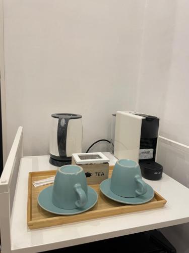 dos tazas y platillos sentados en un mostrador con una cafetera en THE ROOM 115, en Roma