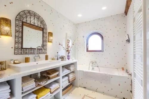 uma casa de banho com uma banheira, um lavatório e um espelho. em Les Herbes Folles em Canouville