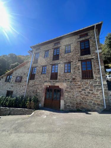 un edificio de piedra con el sol en el cielo en Casa Rural Basiver - Habitación Pico Samelar en Armaño