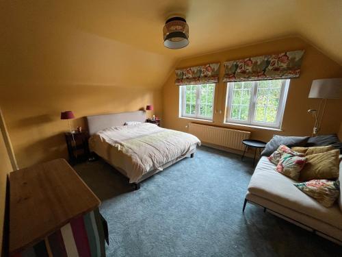 ein Schlafzimmer mit einem Bett und einem Sofa sowie zwei Fenstern in der Unterkunft Charmante maison familiale in Kraainem