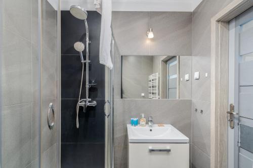 La salle de bains est pourvue d'une douche et d'un lavabo. dans l'établissement Borkowska Standard Apartment, à Cracovie