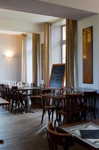 une salle à manger avec tables, chaises et fenêtres dans l'établissement Golf de Rebetz- Domaine de Rebetz, à Chaumont-en-Vexin