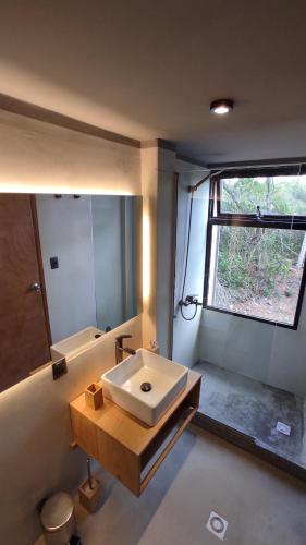 baño con lavabo blanco y ventana en Gran Vista y Tranquilidad en Villa Serrana