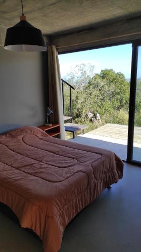 ein Schlafzimmer mit einem Bett und einem großen Fenster in der Unterkunft Gran Vista y Tranquilidad in Villa Serrana