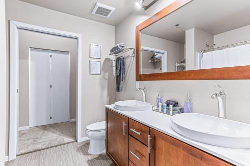 a bathroom with two sinks and a toilet and a mirror at 2 King Bed Spacious Apt Downtown Close to it All in Ann Arbor