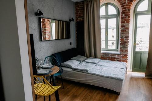 a bedroom with a bed and a table and a brick wall at VS Apartments - apartament nr 34 in Łódź