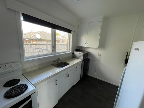 a small kitchen with a sink and a window at Sunny 2bdrm home close to Hospital & Gardens in Hamilton