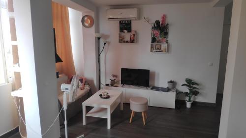 sala de estar con escritorio, TV y silla en Anna's apartments, en Alicante