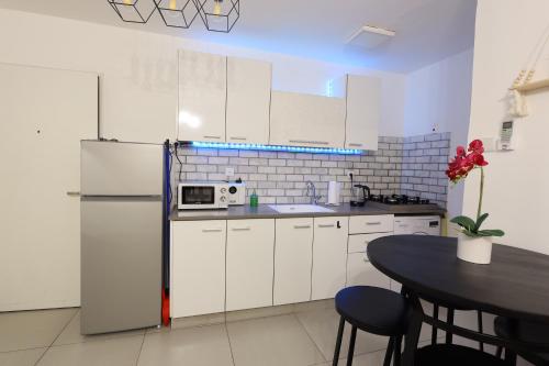 a white kitchen with a refrigerator and a table at הטרקלין של שלמה. דירה יפה וחדשה 5 דקות נסיעה מהים in Ashqelon