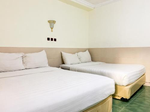 two beds sitting next to each other in a room at Musafira Hotel Syariah Malioboro Yogyakarta Mitra RedDoorz in Yogyakarta