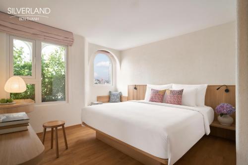 a bedroom with a large white bed and two windows at Silverland Bến Thành in Ho Chi Minh City