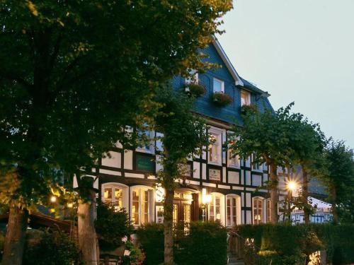 een blauw-wit gebouw met bomen ervoor bij Gasthof Heimes in Schmallenberg