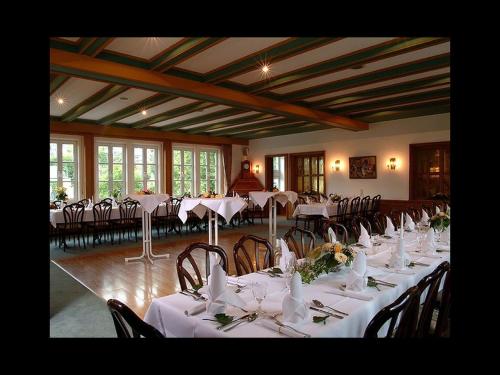 een kamer met tafels en stoelen met witte tafelkleden bij Gasthof Heimes in Schmallenberg