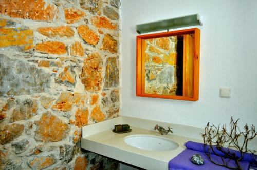 a bathroom with a sink and a stone wall at Dimitra Studios in Aegiali