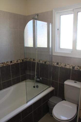 a bathroom with a tub and a toilet and a window at Maricosta Villas in Protaras