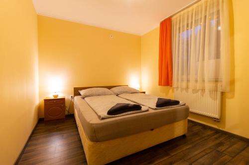 a bedroom with a bed and a window with two lamps at Szelidi Apartmanok in Dunapataj