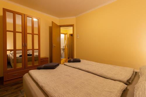two beds in a room with yellow walls at Szelidi Apartmanok in Dunapataj