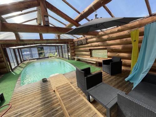 - une piscine dans un bâtiment en bois avec un parasol dans l'établissement Les Fourniols, à Saint-Mathurin-Léobazel