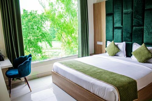 a bedroom with a bed and a window and a chair at Hotel Global Inn by T&G in Amritsar
