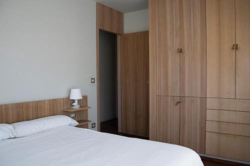 1 dormitorio con cama blanca y armarios de madera en Maravilloso apartamento de playa en la paradisíaca Illa de Arousa, en A Illa de Arousa