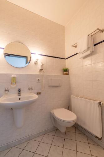 a bathroom with a sink and a toilet and a mirror at Landhotel Elkemann in Ahaus