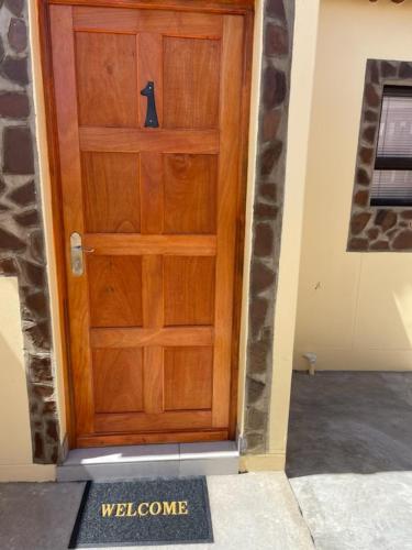 a wooden door with a welcome mat in front of it at The Oasis Accommodation in Lüderitz