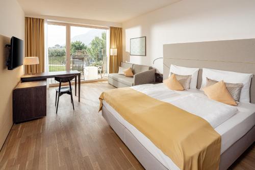 a hotel room with a large bed and a desk at Hotel Thalhof am See in Caldaro