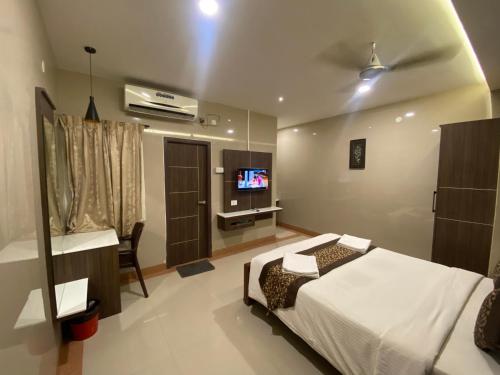 um quarto com uma cama e uma televisão de ecrã plano em Hotel Sivas Regency em Theni